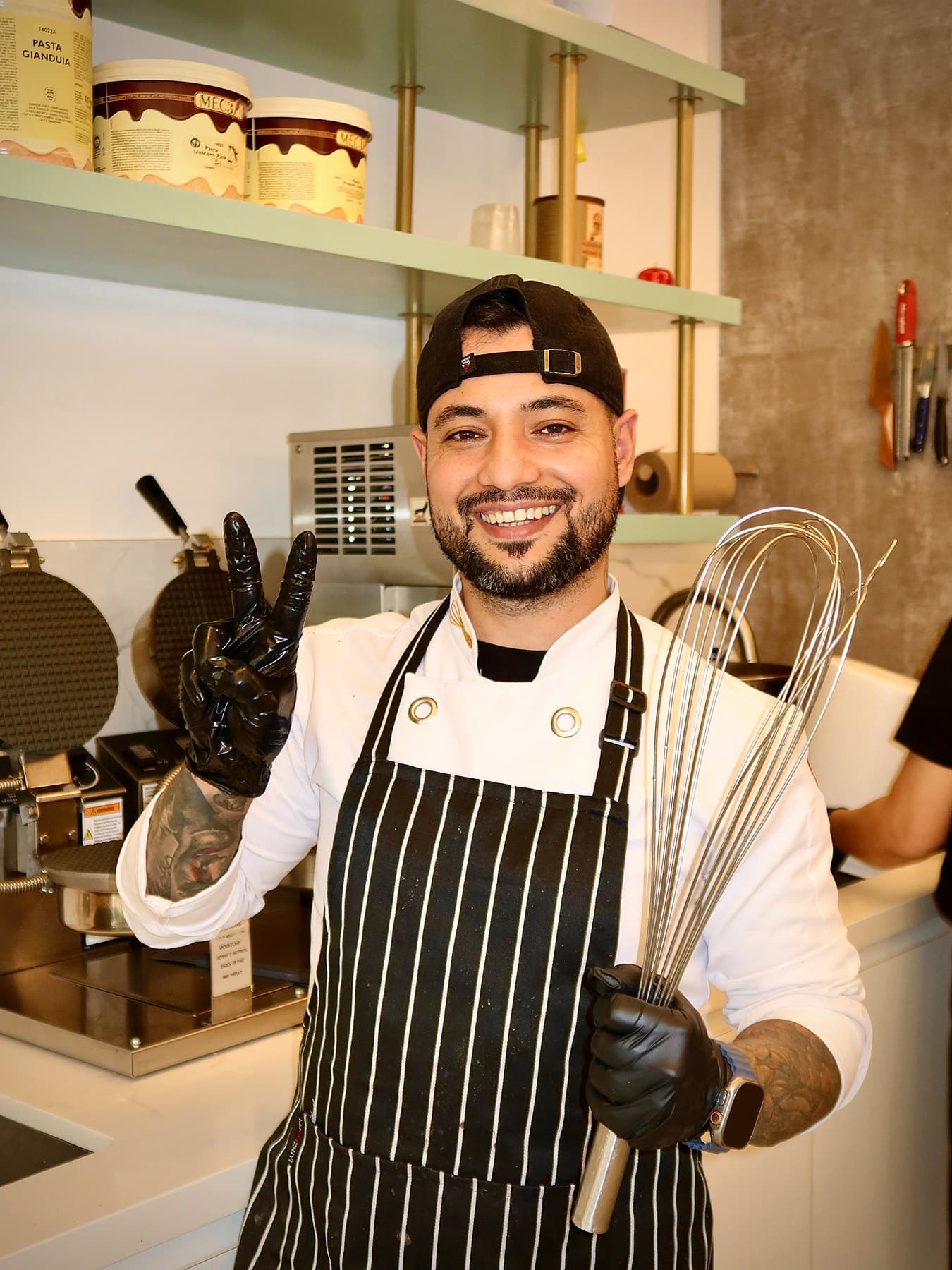 Can Montana behind the counter at Puuffy, holding a whisk and smiling