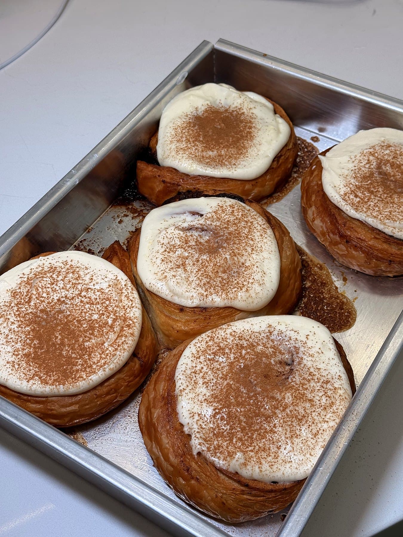 Tray of cinnamon bun croissants topped with frosting and cinnamon