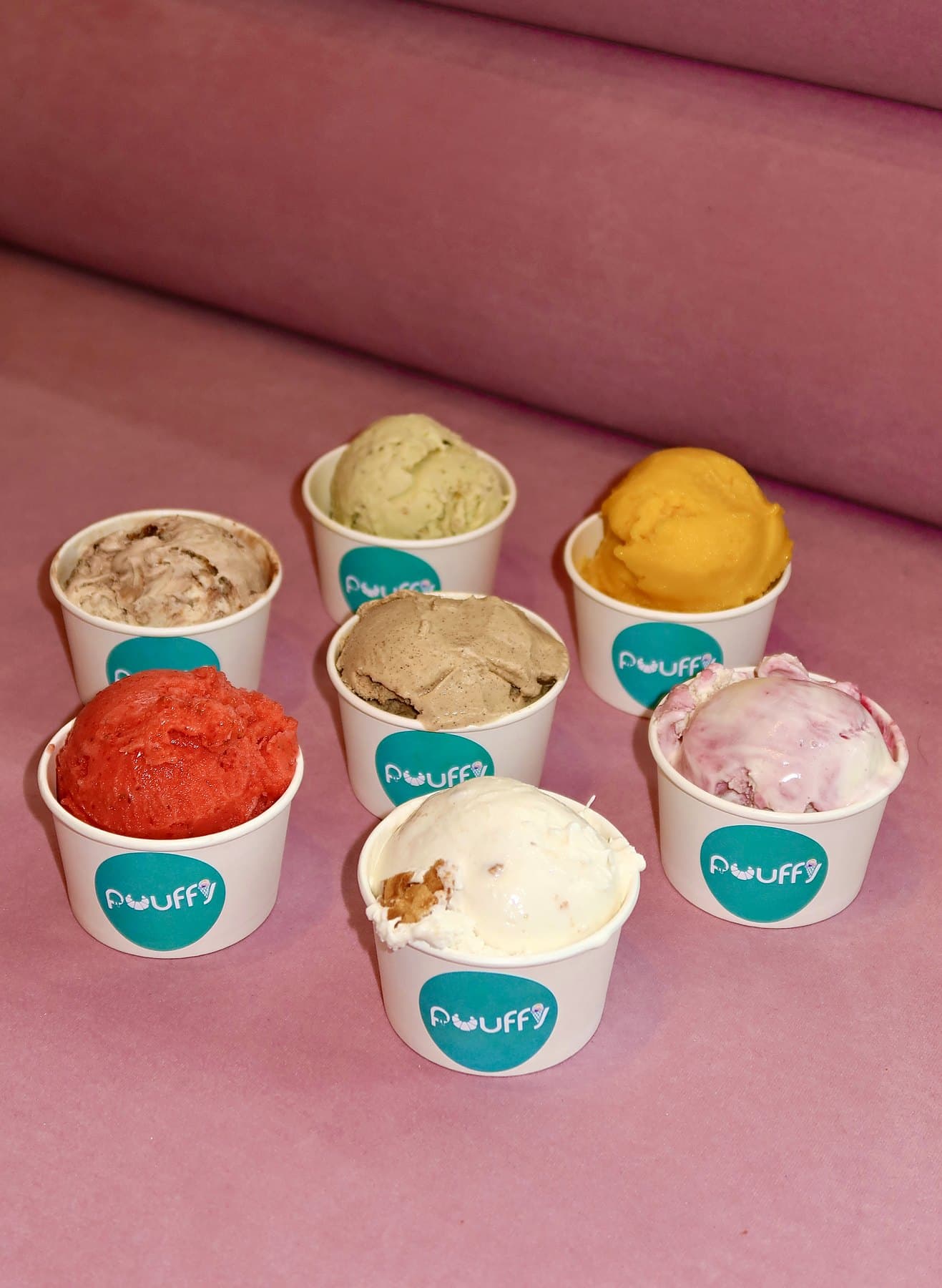 Seven cups of ice cream and sorbet on pink velvet
