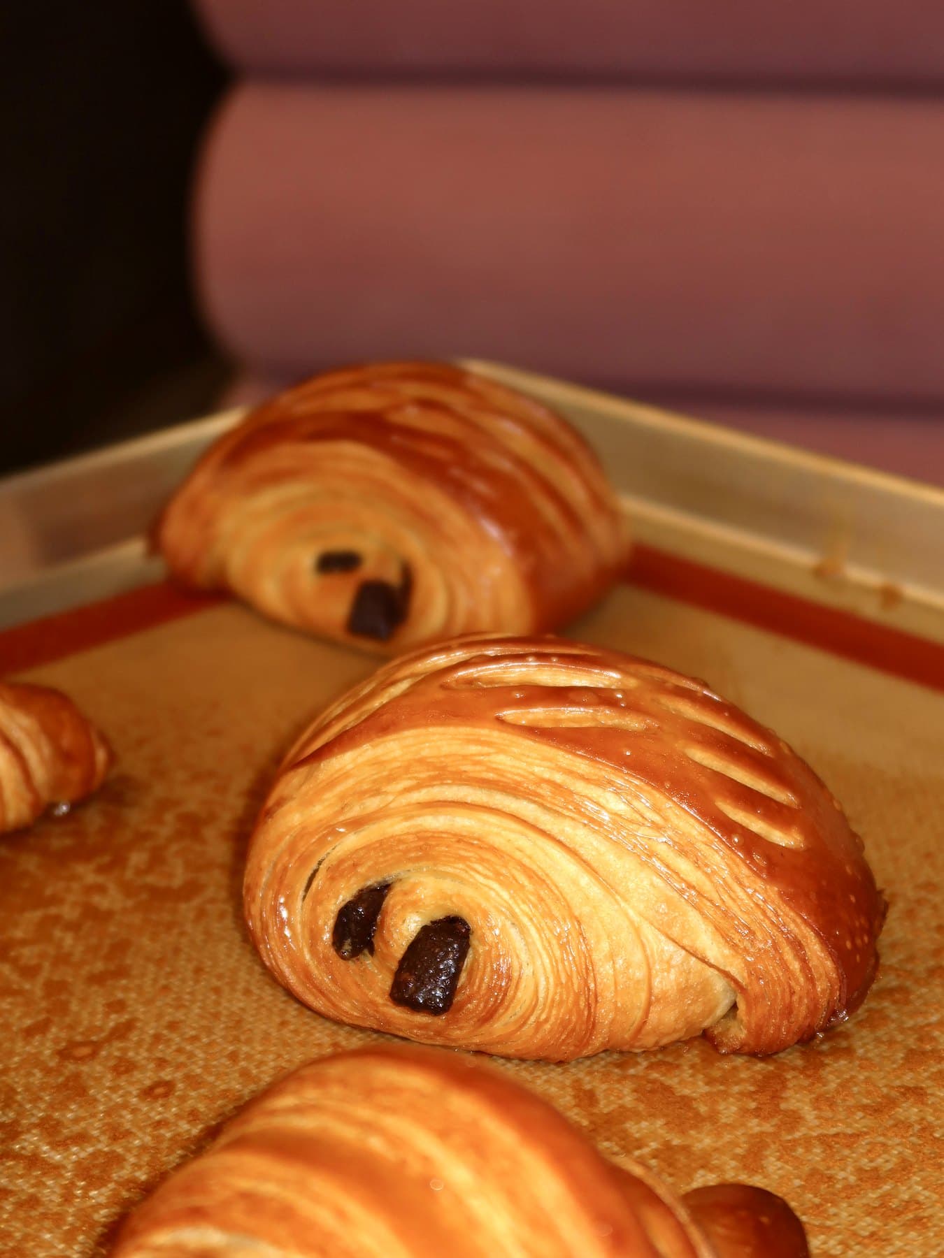 Pain au chocolat on a baking tray with chocolate peeking out of the ends