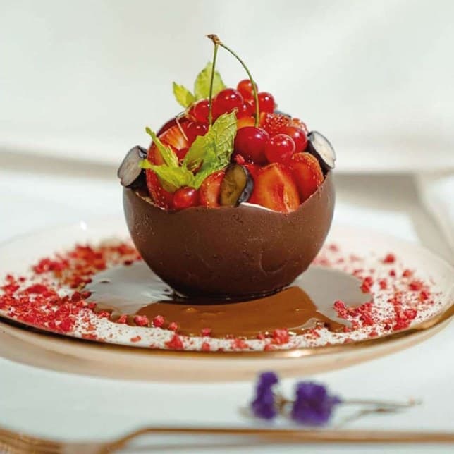 Edible dark chocolate bowl filled with mixed berries and mint