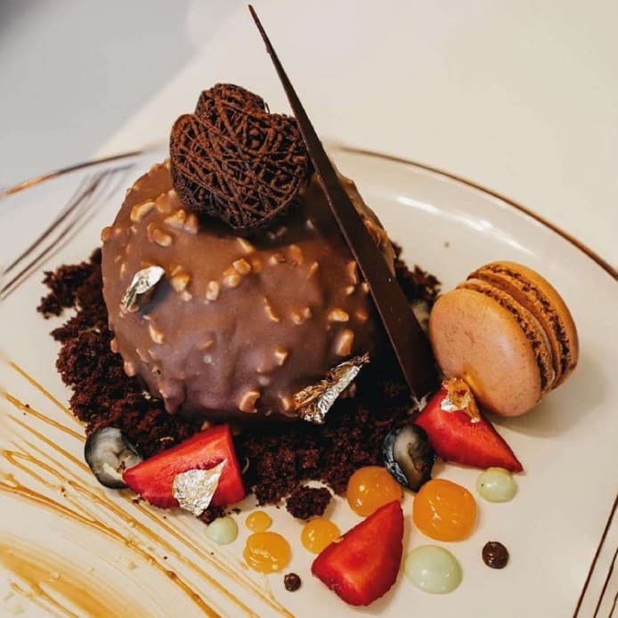 Hazelnut praline dome dessert with chocolate sail and macaron