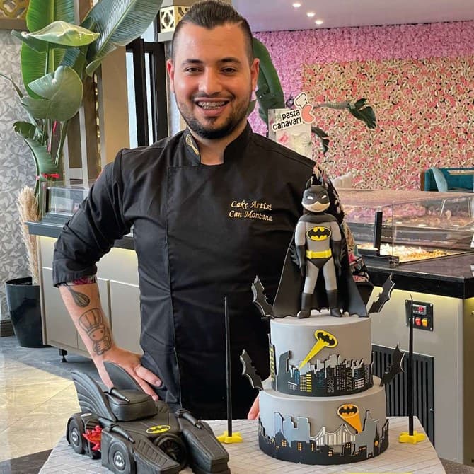 Can Montana next to a sculpted Batman-themed celebration cake with a Batmobile